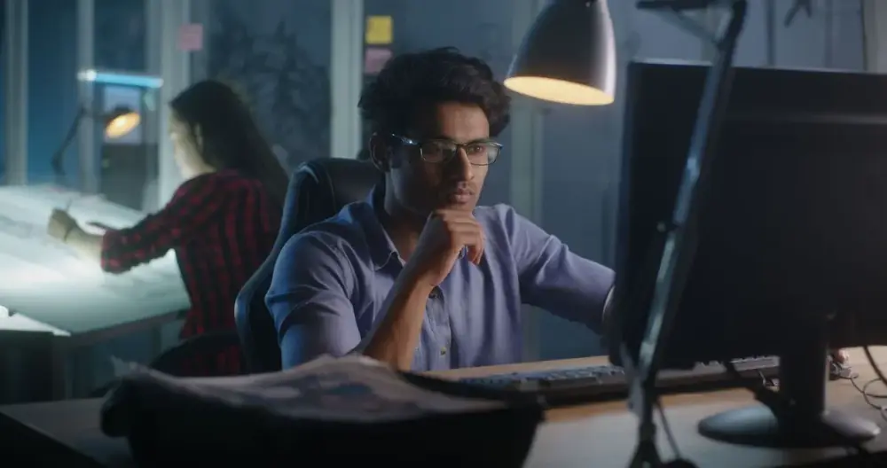 Prakat engineer reviewing code at a workstation